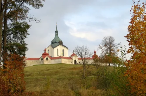 Poutní kostel svatého Jana Nepomuckého na Zelené hoře ve Žďáru nad Sázavou na podzim, s ambitem a stromy v popředí