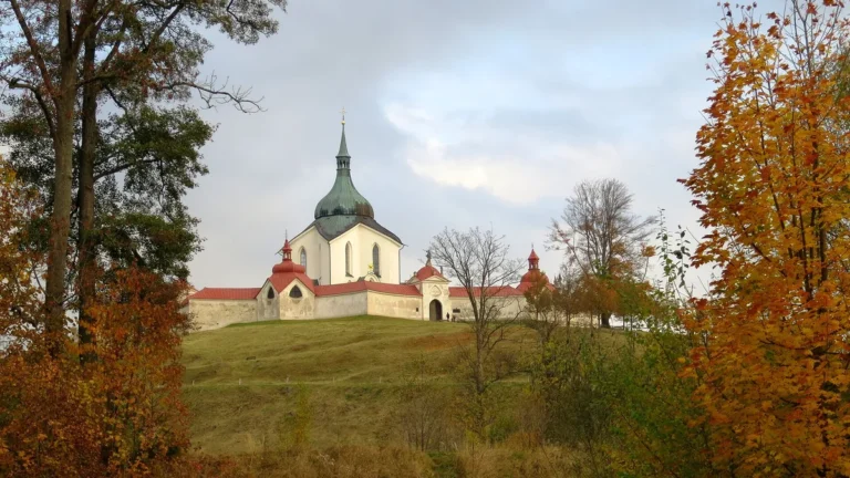 Poutní kostel svatého Jana Nepomuckého na Zelené hoře ve Žďáru nad Sázavou na podzim, s ambitem a stromy v popředí