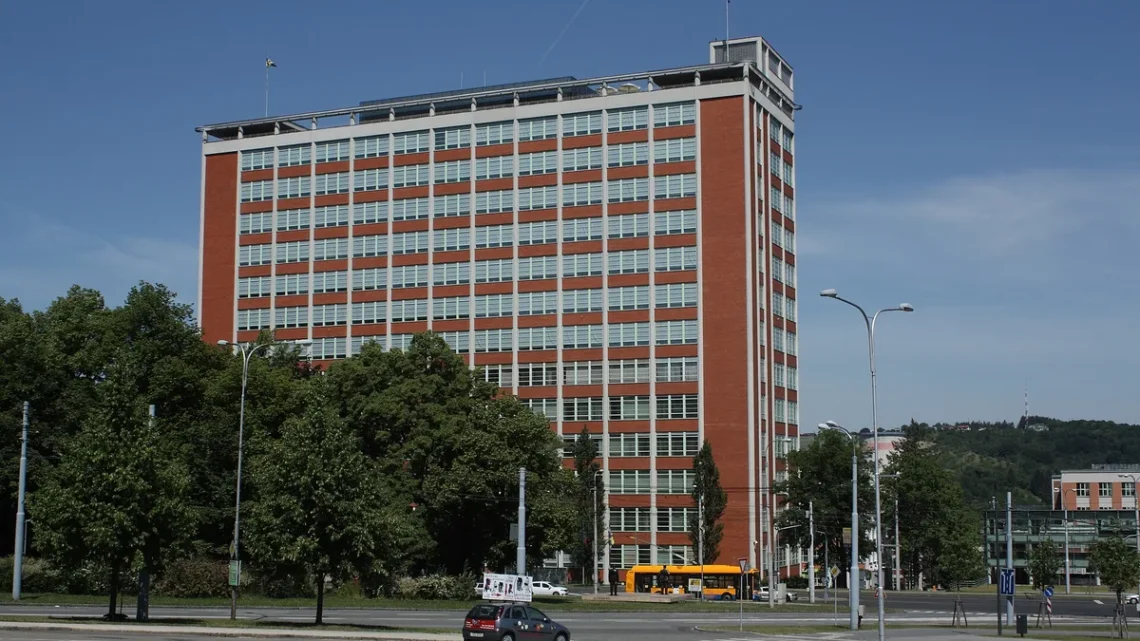 Baťův mrakodrap, budova 21 ve Zlíně, cihlová výšková budova s pásy oken za stromy na třídě Tomáše Bati