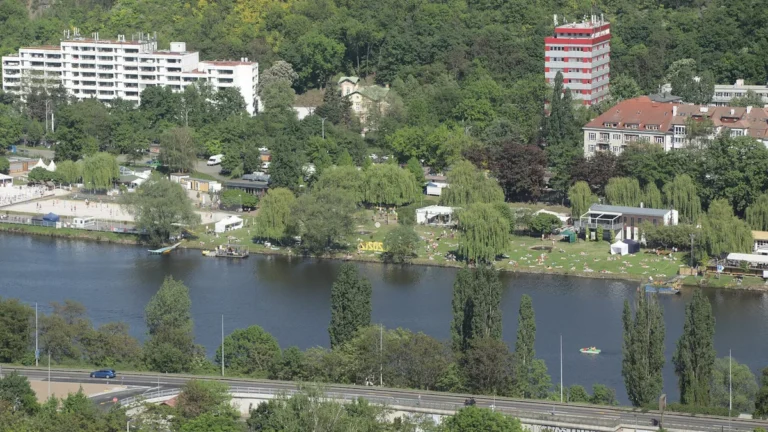 Žluté lázně v pražském Podolí, travnatá pláž s návštěvníky na břehu Vltavy